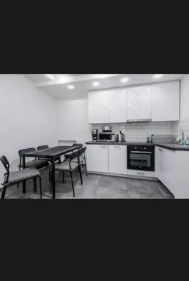 a kitchen with white cabinets and a table and chairs at Beer Street Apartment in Kraków