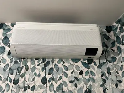 a white air conditioner sitting on a bed at Nenufar Cracow Garden Kraków Parter Free Darmowy Parking Ogród Netflix Klimatyzacja in Kraków