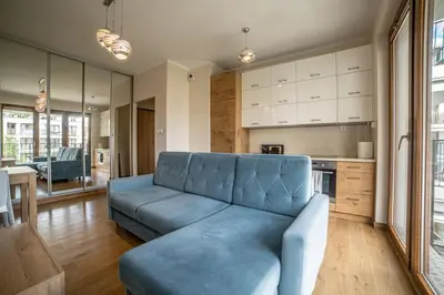 a living room with a blue couch and a kitchen at Jop in Kraków