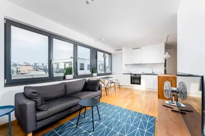 a living room with a couch and a kitchen at Skowronia Modern Apartment by BookingHost in Kraków