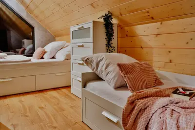 a bed in a wooden room with a large window at Wzgórza Jordanowskie in Jordanów