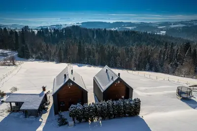 a snow covered slope with a ski lodge on a mountain at Wzgórza Jordanowskie in Jordanów