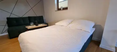 a bedroom with a bed and a green couch at Apartament Miód Malina in Olszówka