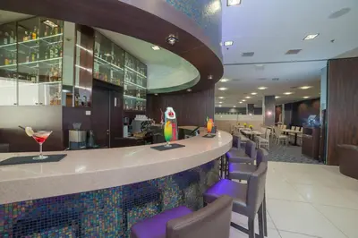 a restaurant with a bar with purple chairs at Premier Kraków Hotel in Kraków