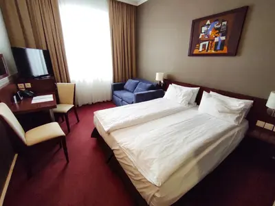 a hotel room with a large bed and a chair at Premier Kraków Hotel in Kraków