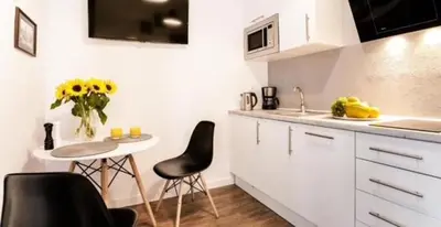 a kitchen with a table and chairs and a table with flowers at Old Town Apt - Topolowa studio T33 in Kraków