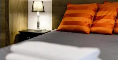 a bed with an orange pillow and a lamp on a night stand at Old Town Apt - Topolowa studio T33 in Kraków