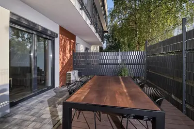 a wooden table on a patio next to a fence at Place Oswiecim - underground parking, air conditioning, Self Check In in Oświęcim