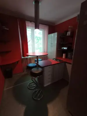 a kitchen with red walls and a table and stools at Apartament Humberta in Kraków