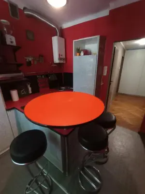 a kitchen with a red table and four stools at Apartament Humberta in Kraków