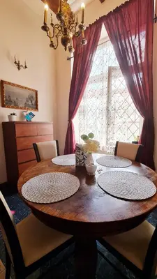 a dining room table with four chairs and a large window at Komfortowy Apartament na ul Brackiej 6B in Kraków