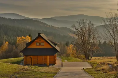a small cabin on a hill with mountains in the background at Domki 15 szczytów in Zawoja