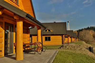 a wooden cabin with a table and chairs on a patio at Domki 15 szczytów in Zawoja