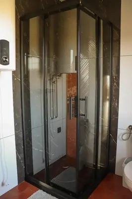 a glass shower in the corner of a bathroom at Domki 15 szczytów in Zawoja