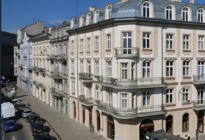 a large white building with cars parked on a street at Old Town Apt - Wielopole studio W6 in Kraków