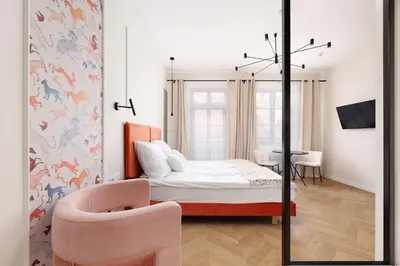 a bedroom with a bed and a pink chair at Hetman Main Square Apartments in Kraków