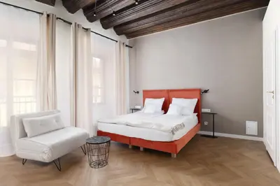 a bedroom with a bed and a chair at Hetman Main Square Apartments in Kraków