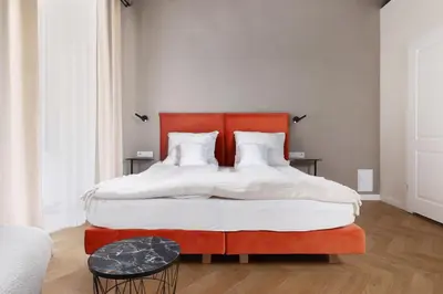 a bedroom with a large bed with an orange headboard at Hetman Main Square Apartments in Kraków