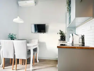 a kitchen with a white table and white chairs at Welcoming Apartments with bedrooms and Air Conditioning, city center in Kraków