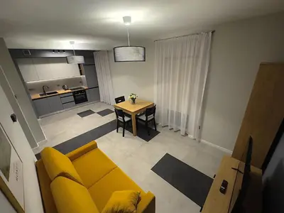 a living room with a yellow couch and a table at Apartamenty N, Trąbki in Wieliczka