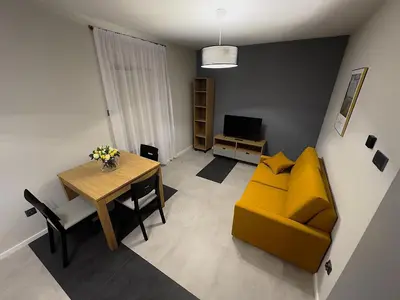 a living room with a yellow couch and a table at Apartamenty N, Trąbki in Wieliczka