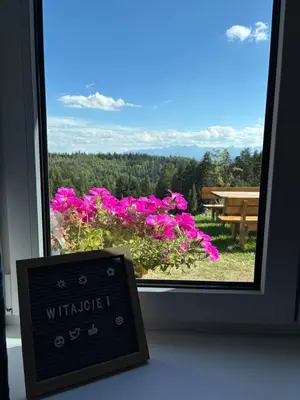 a sign in front of a window with pink flowers at Apartament Zielone Wzgórze Pod Turbaczem in Nowy Targ