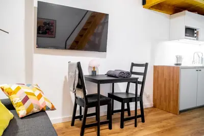 a small black table and chairs in a room with a kitchen at Piano Apartments in Kraków