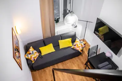 a living room with a black couch with yellow pillows at Piano Apartments in Kraków