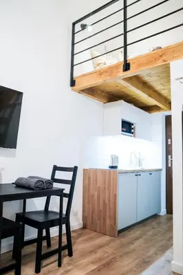 a dining room with a table and a kitchen at Piano Apartments in Kraków