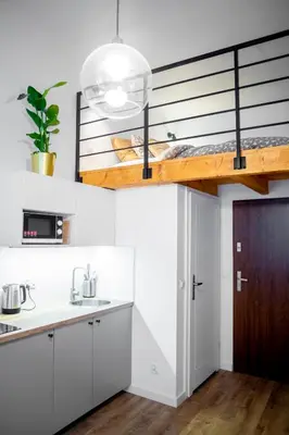 a kitchen with white cabinets and a loft bed at Piano Apartments in Kraków