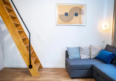 a living room with a blue couch and a staircase at Piano Apartments in Kraków