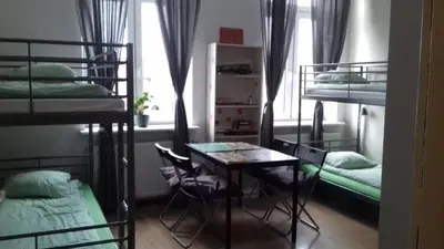 a room with bunk beds and a table and a desk at Art Hostel in Kraków