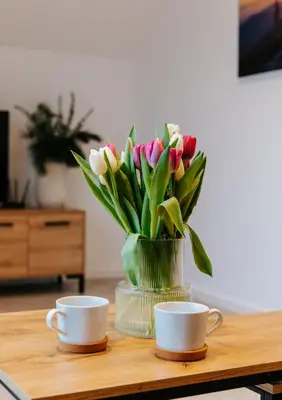 a vase of flowers sitting on a table with two cups at Apart Home Raba Wyżna in Raba Wyżna