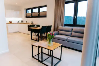 a living room with a couch and a table with flowers at Apart Home Raba Wyżna in Raba Wyżna