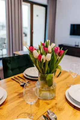 a vase of pink and white tulips on a table at Apart Home Raba Wyżna in Raba Wyżna