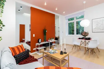 a living room with an orange accent wall at Apartment near Main Station - Bosacka 8 street in Kraków