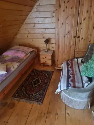 a bedroom with a bed and a chair in a log cabin at Rancho w Dolinie in Skomielna Biała