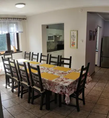 a dining room with a table and chairs and a kitchen at Kwatery U Adama Zawoja in Zawoja