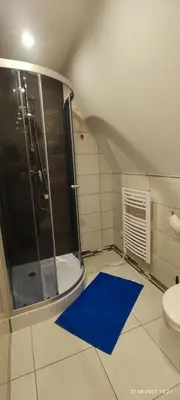 a bathroom with a shower and a blue rug at Kwatery U Adama Zawoja in Zawoja