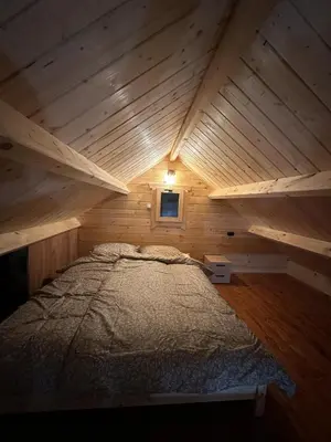 a large bed in a wooden cabin with a window at Piekielne zacisze in Klecza Dolna