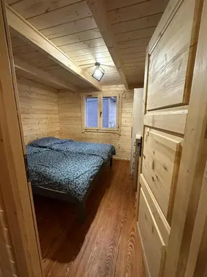 a small bedroom with a bed in a wooden cabin at Piekielne zacisze in Klecza Dolna