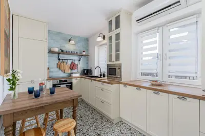 a kitchen with white cabinets and a wooden table at Luxury apartment in a truly PERFECT location in Kraków