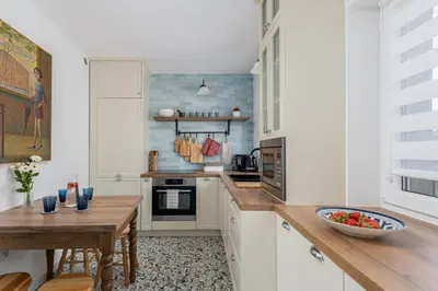 a kitchen with white cabinets and a wooden table at Luxury apartment in a truly PERFECT location in Kraków