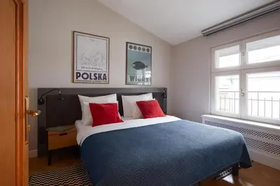 a bedroom with a bed with blue pillows and a window at STRADONIA Serviced Apartments in Kraków