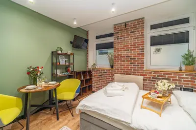 a living room with a bed and a brick wall at Kraków Grzegórzki Studio - Central Station Nearby - by Rentujemy in Kraków