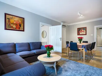 a living room with a blue couch and a table at Apartments Rynek Glowny in Kraków