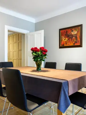 a table with a vase of red roses on it at Apartments Rynek Glowny in Kraków