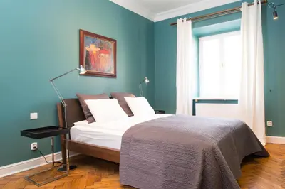 a bedroom with a bed with a blue wall at Apartments Rynek Glowny in Kraków