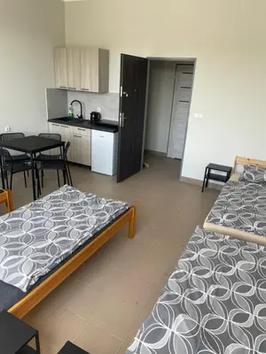a room with two beds and a table and a kitchen at Noclegi Eliza in Dąbrowa Górnicza
