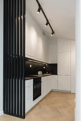 a kitchen with white cabinets and black appliances at Metropolis Design Apartments in Kraków